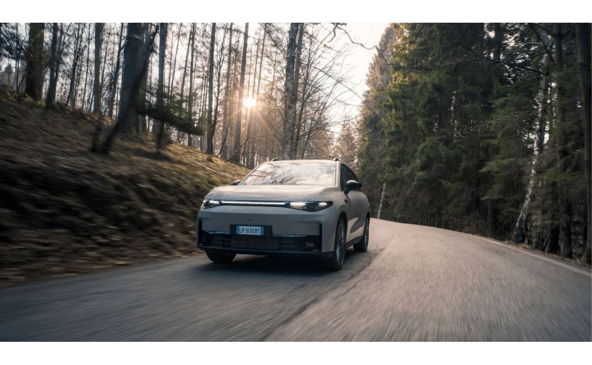 Siv Leapmotor C10 na gozdni cesti s sončno svetlobo med drevesi