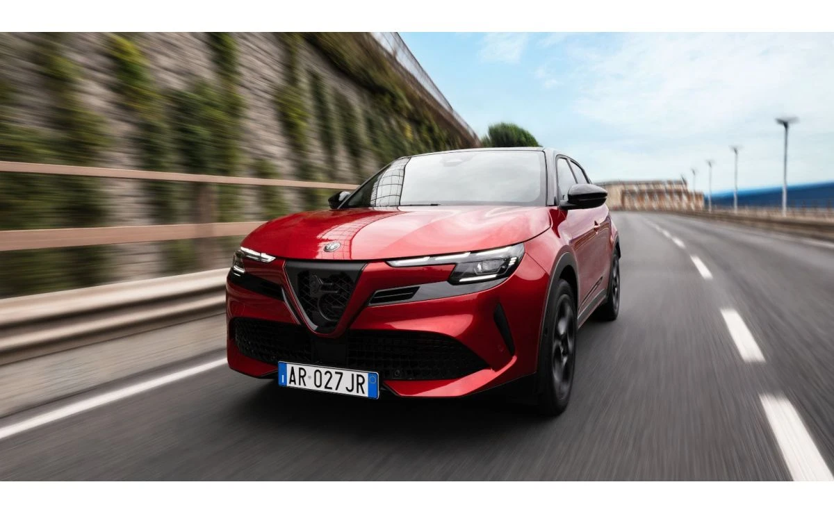 Rdeča Alfa Romeo Junior med vožnjo po mestni cesti