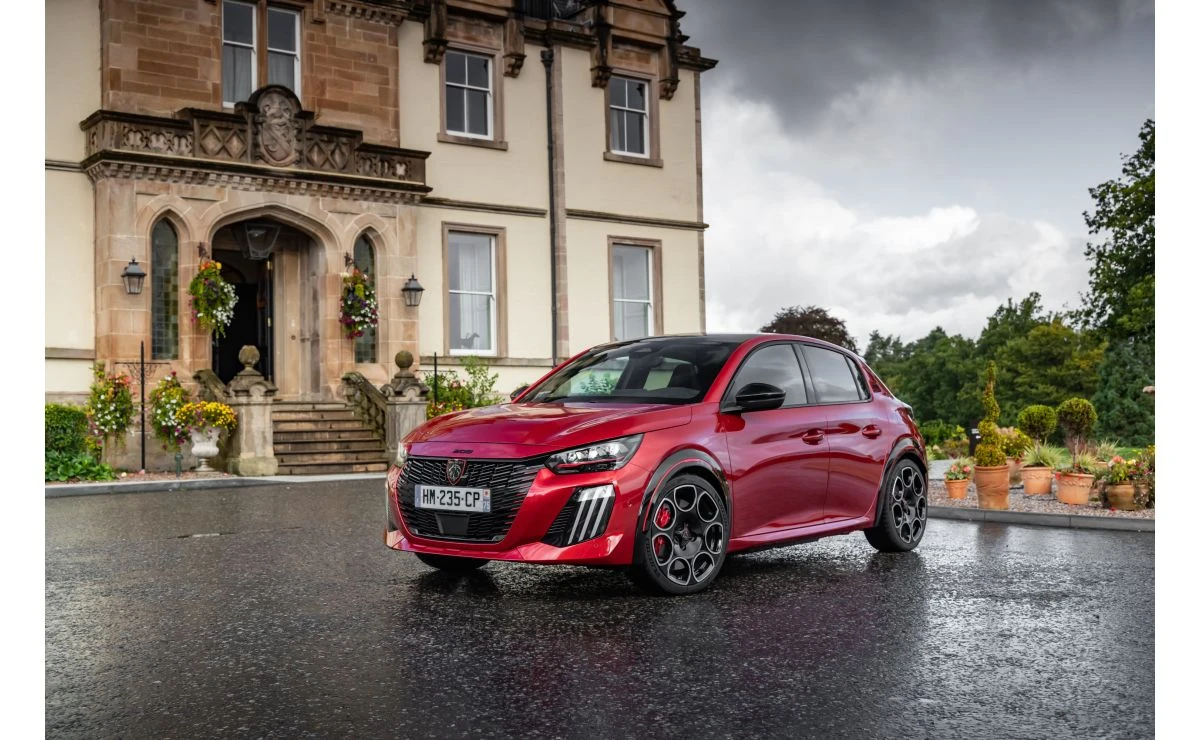 Rdeči Peugeot E-208 GTi na mokrem dvorišču pred stavbo