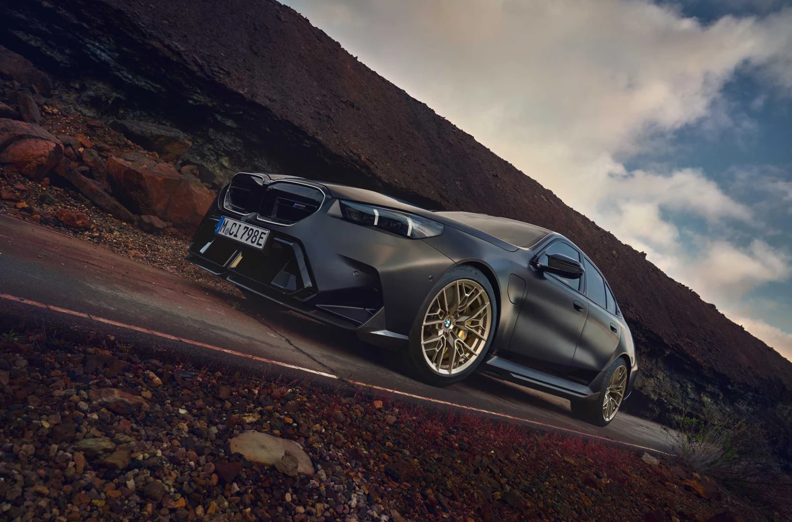 Siv BMW M5 z bronastimi platišči na gorski cesti