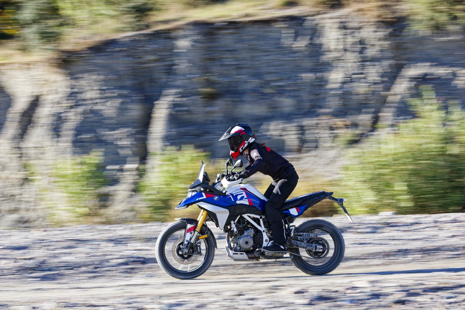 Voznik na modro-belem motociklu BMW F 450 GS na kamniti poti