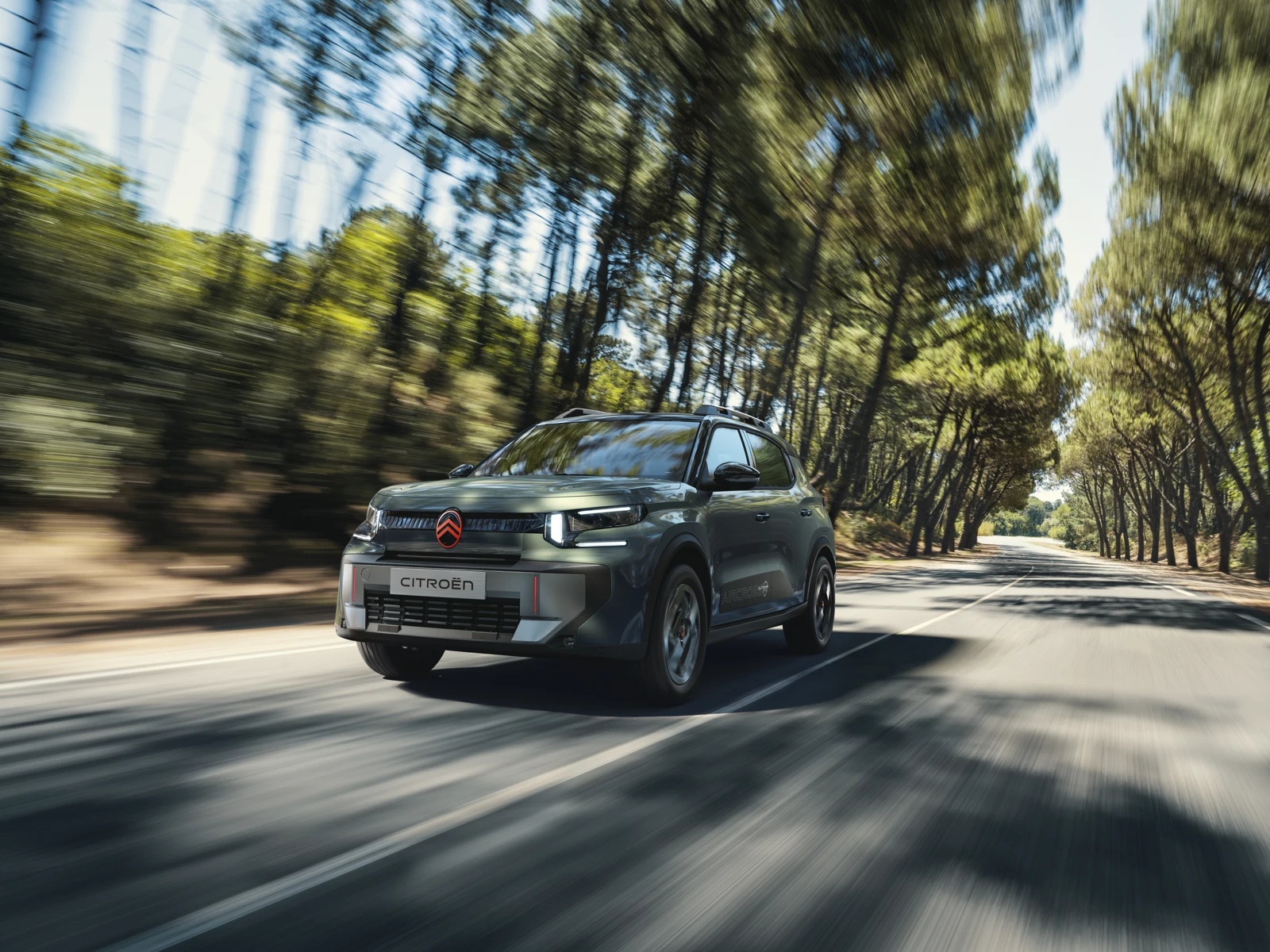 Zeleni Citroën C3 Aircross Outdoor med vožnjo po cesti med drevesi