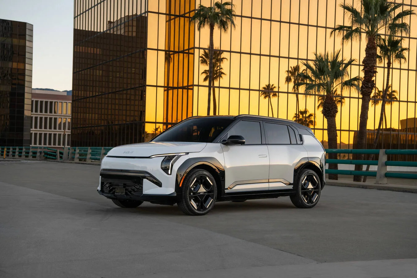 Kia EV3 ob stavbi z odsevi palm