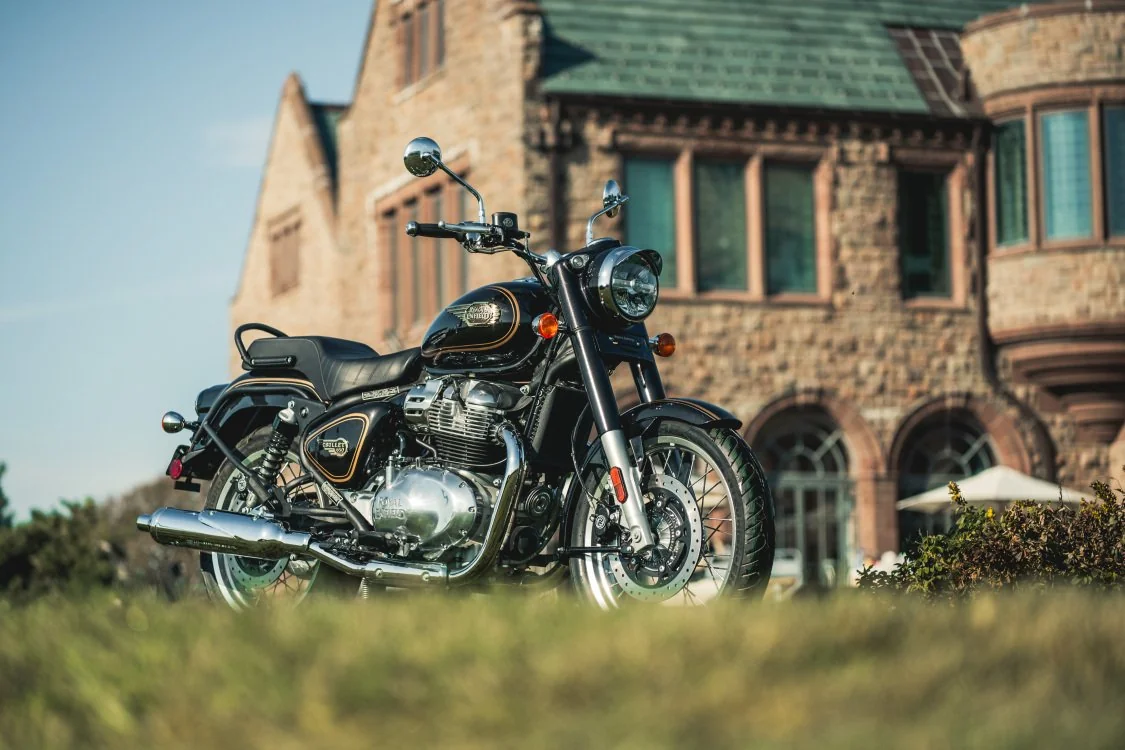 Črni Royal Enfield Bullet 650 s kromiranima izpuhoma pred kamnito stavbo